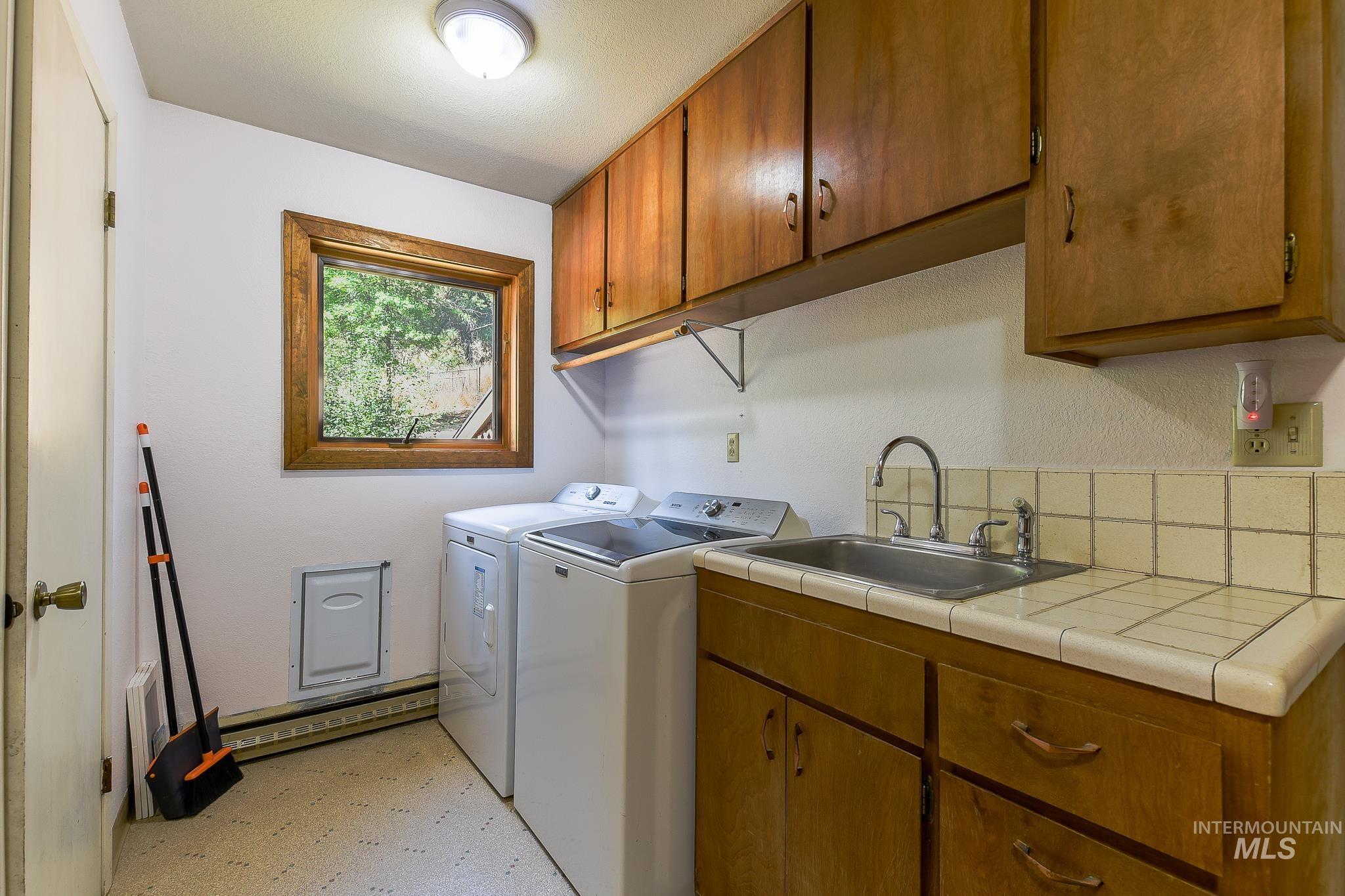 1045 Joyce Road Moscow, ID 83843 - Photo 12 of 50 Laundry area featuring wood cabinetry, a utility sink, and tiled countertops