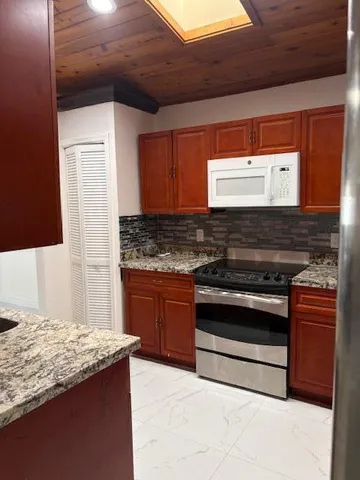 a kitchen with stainless steel appliances granite countertop wooden cabinets and a stove top oven