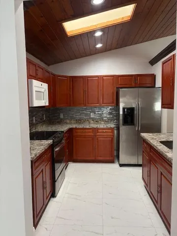 a kitchen with stainless steel appliances granite countertop wooden cabinets sink and stove
