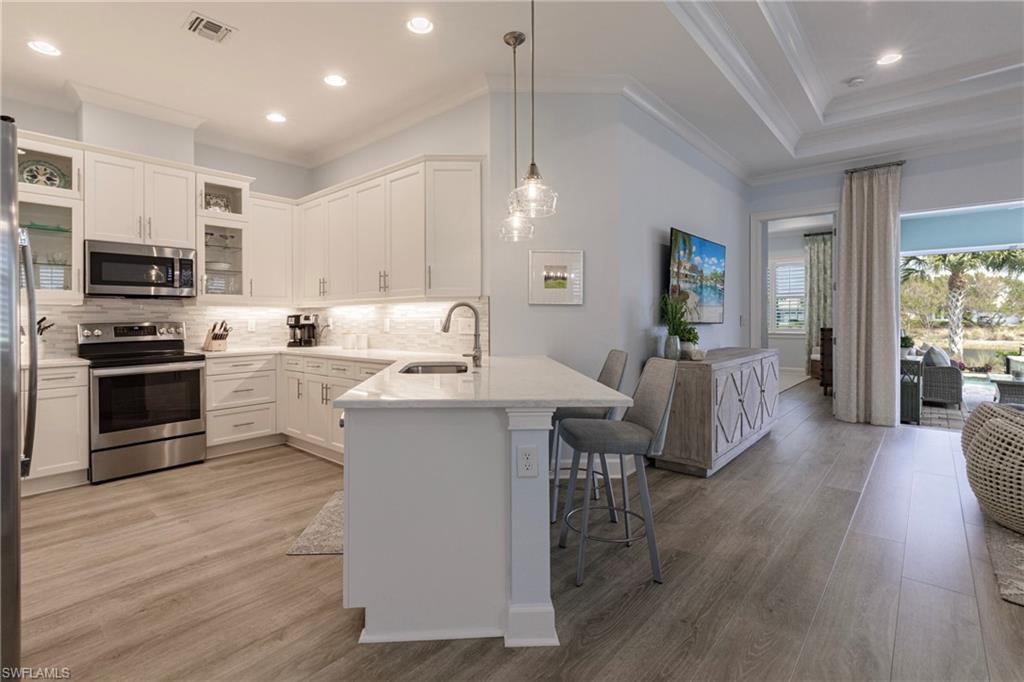 5906 Haiti Drive Naples, FL 34113 - Photo 14 of 44 a living room with stainless steel appliances furniture a fireplace a flat screen tv and a wooden floor