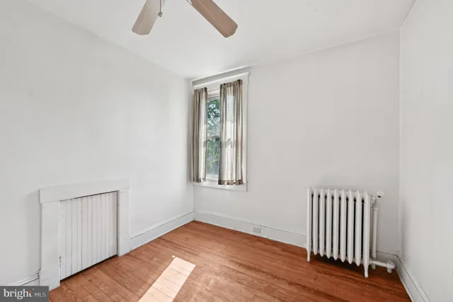 an empty room with wooden floor chandelier fan and windows