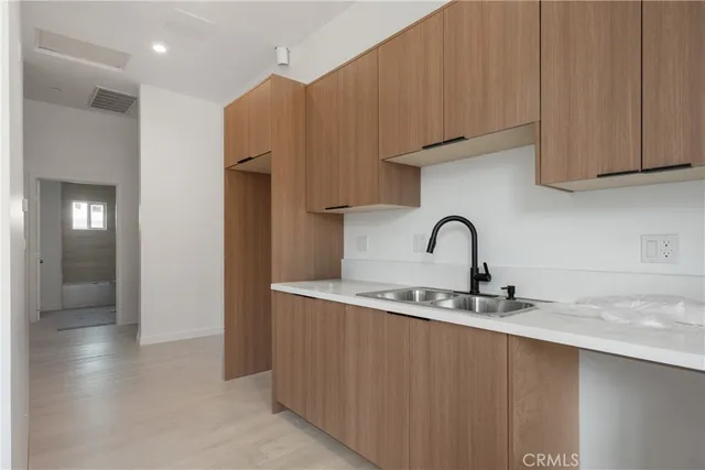 a kitchen with stainless steel appliances granite countertop a sink a stove and a refrigerator with wooden cabinets