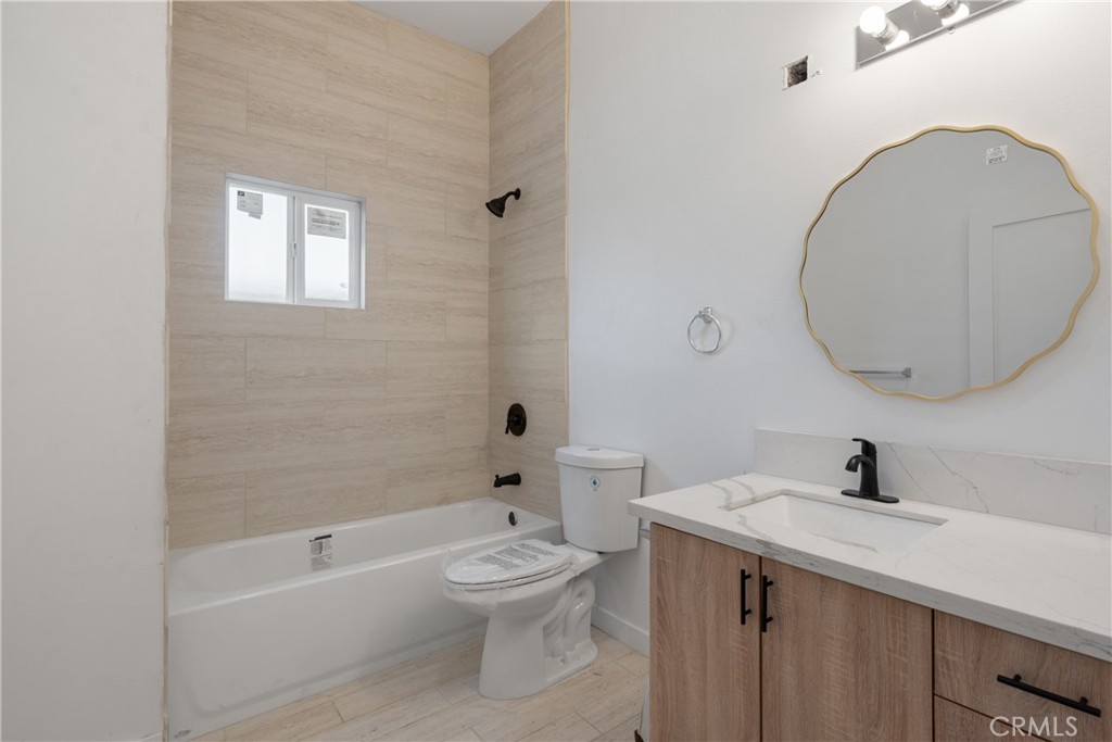 3929 Brighton Avenue, Unit 1/2 Los Angeles, CA 90062 - Photo 5 of 7 a bathroom with a toilet a sink a mirror and bathtub