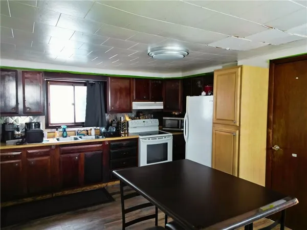 a kitchen with granite countertop a refrigerator stove top oven a sink dishwasher and cabinets