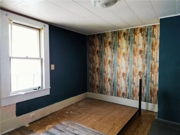 a view of empty room with wooden floor and large window