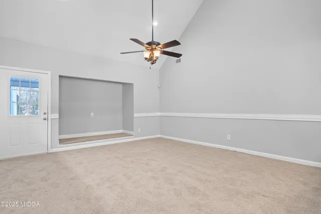 a view of an empty room with a chandelier fan