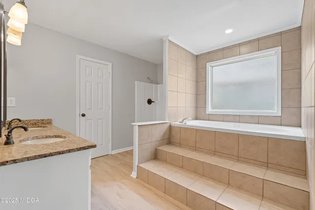 a bathroom with a granite countertop sink a mirror and shower