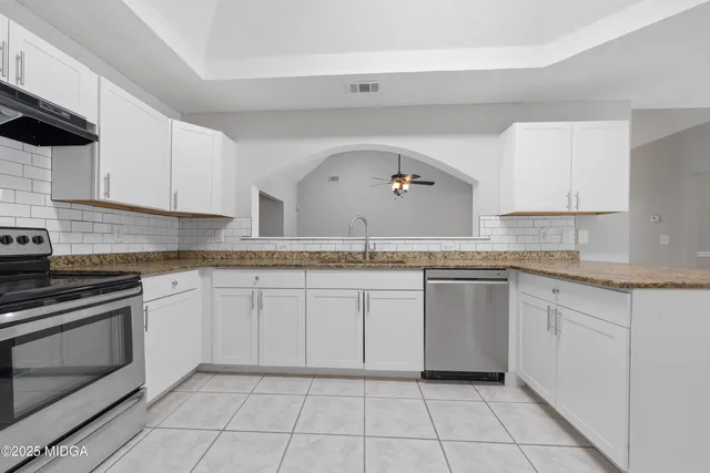 a kitchen with granite countertop white cabinets and stainless steel appliances