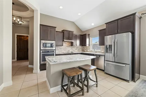 a kitchen with stainless steel appliances granite countertop a refrigerator and a stove top oven