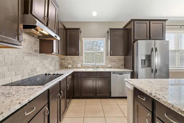 a kitchen with kitchen island granite countertop a sink stove and refrigerator
