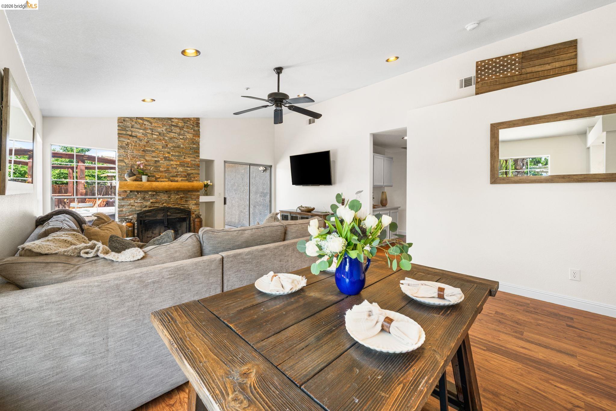 1186 El Rio Court Livermore, CA 94551 - Photo 11 of 60 Spacious living area featuring a stone fireplace with a substantial wood mantel, a ceiling fan, recessed lighting, and wood-finish flooring