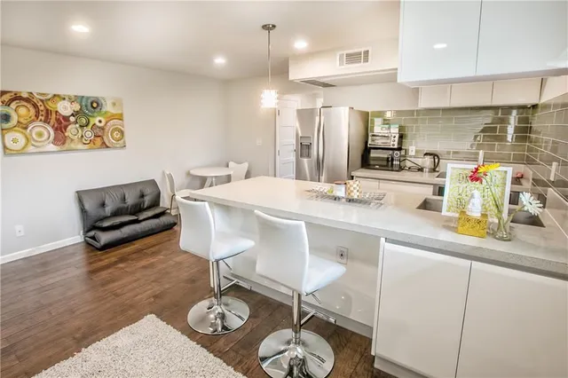 a kitchen with stainless steel appliances granite countertop a sink a stove a refrigerator cabinets and living room view