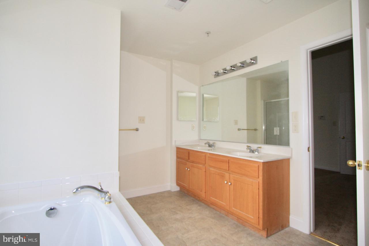 17626 Potter Bell Way Hagerstown, MD 21740 - Photo 14 of 21 a bathroom with a granite countertop sink a mirror and a bathtub