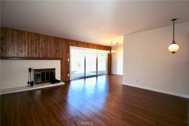 a view of an empty room with wooden floor fireplace and a window