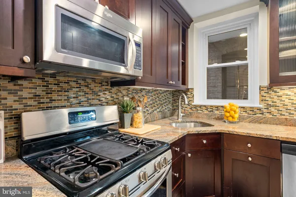 a kitchen with a stove a microwave a sink and cabinets