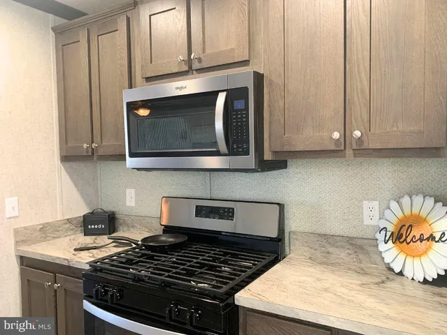 a kitchen with kitchen island granite countertop a sink a counter top space stainless steel appliances and cabinets