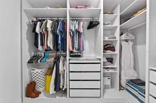a view of walk in closet with clothes and shoes