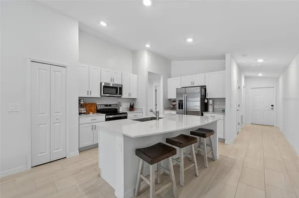 a kitchen with stainless steel appliances a refrigerator a stove a sink a dining table and chairs