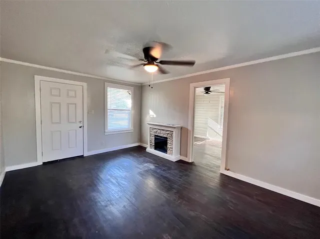a view of an empty room with wooden floor fireplace and a window
