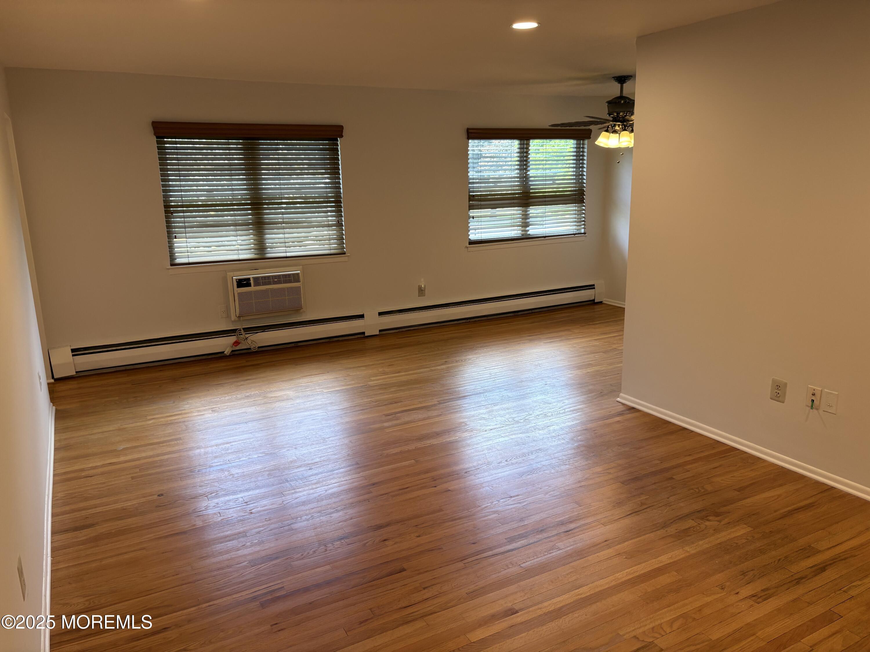 94 Stonehurst Boulevard, Unit E Freehold, NJ 07728 - Photo 3 of 11 an empty room with wooden floor and windows