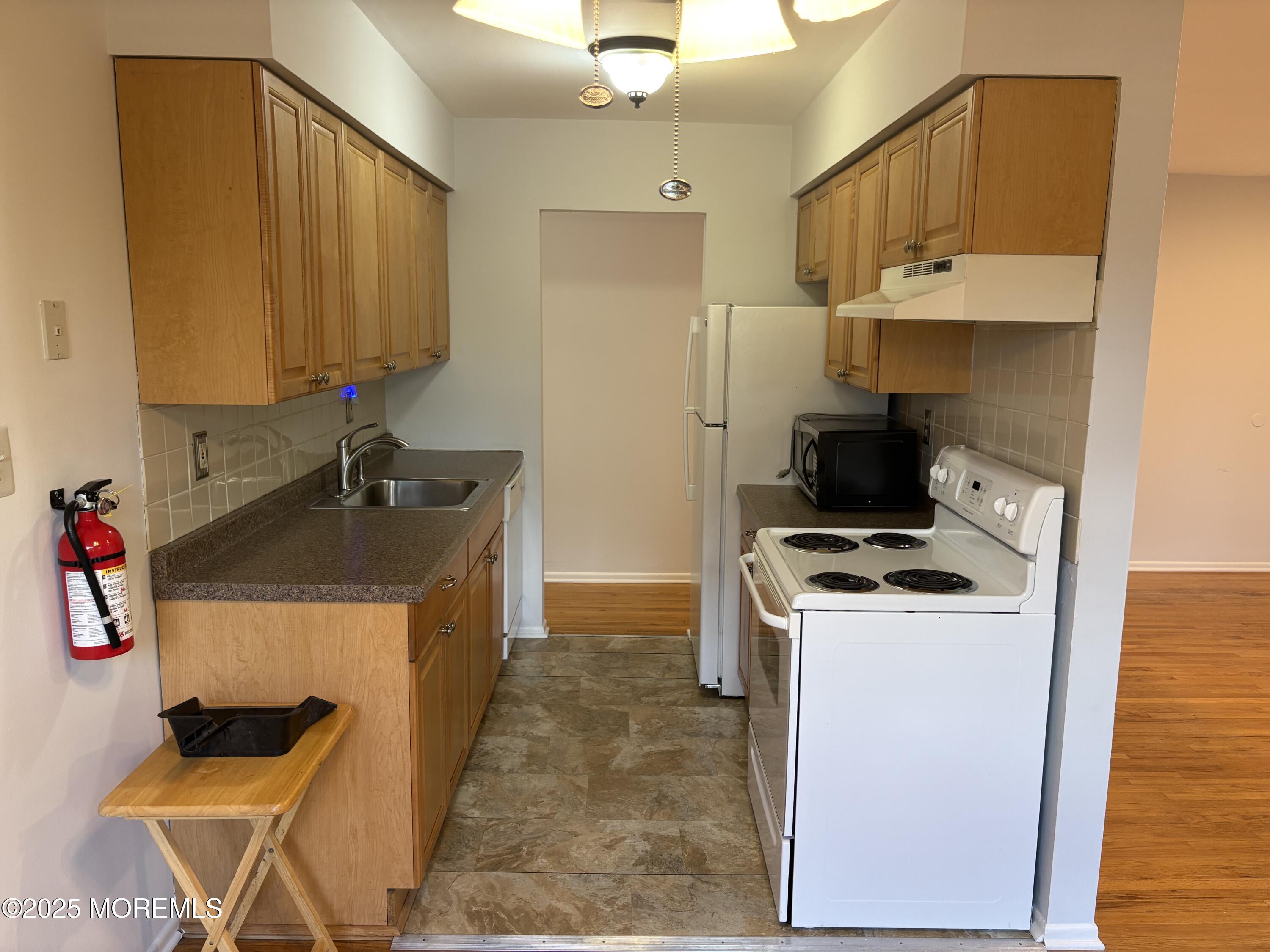 94 Stonehurst Boulevard, Unit E Freehold, NJ 07728 - Photo 6 of 11 a kitchen that has a sink and a stove in it