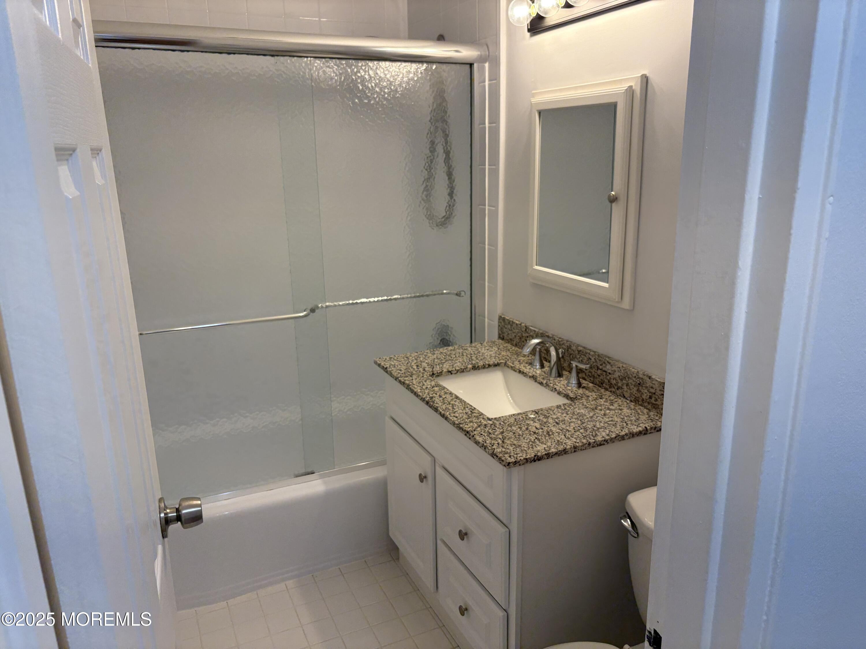 94 Stonehurst Boulevard, Unit E Freehold, NJ 07728 - Photo 8 of 11 a bathroom with a granite countertop sink and a mirror