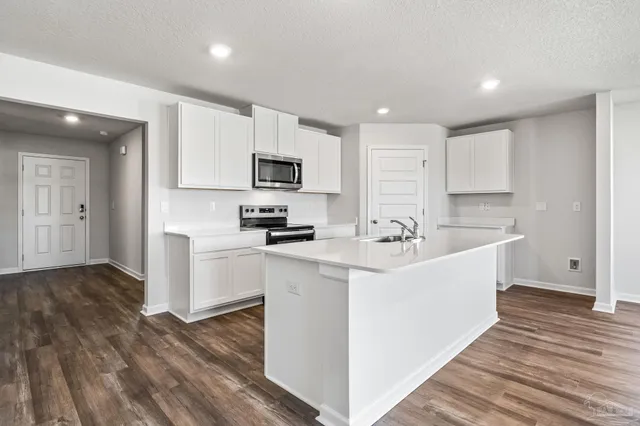 a kitchen with stainless steel appliances a sink a stove a microwave and cabinets