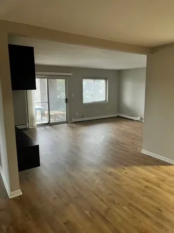 an empty room with wooden floor cabinet and mirror