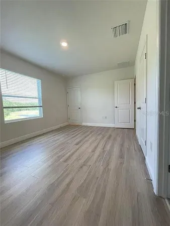 an empty room with wooden floor and windows