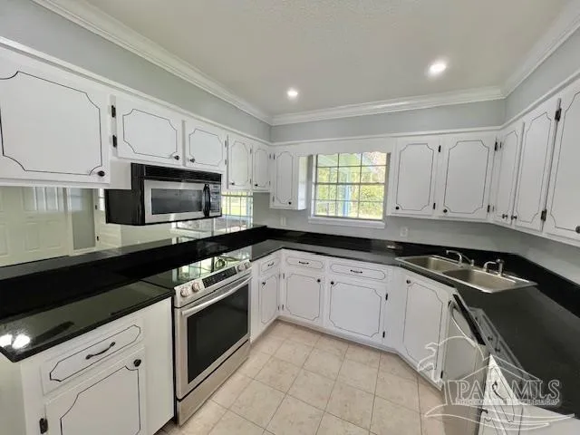 a kitchen with granite countertop white cabinets appliances a sink and a window