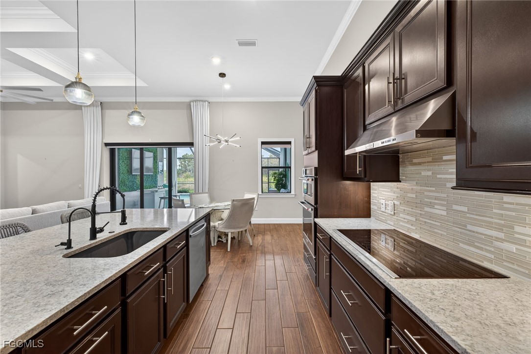 19815 Beverly Park Road Estero, FL 33928 - Photo 12 of 49 a kitchen with stainless steel appliances granite countertop a sink a stove and a wooden floors