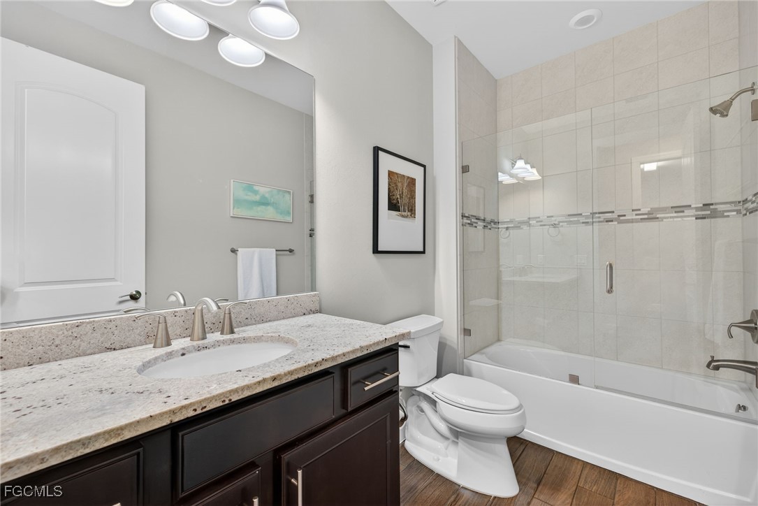 19815 Beverly Park Road Estero, FL 33928 - Photo 23 of 49 a bathroom with a granite countertop sink toilet a large mirror a bathtub and shower