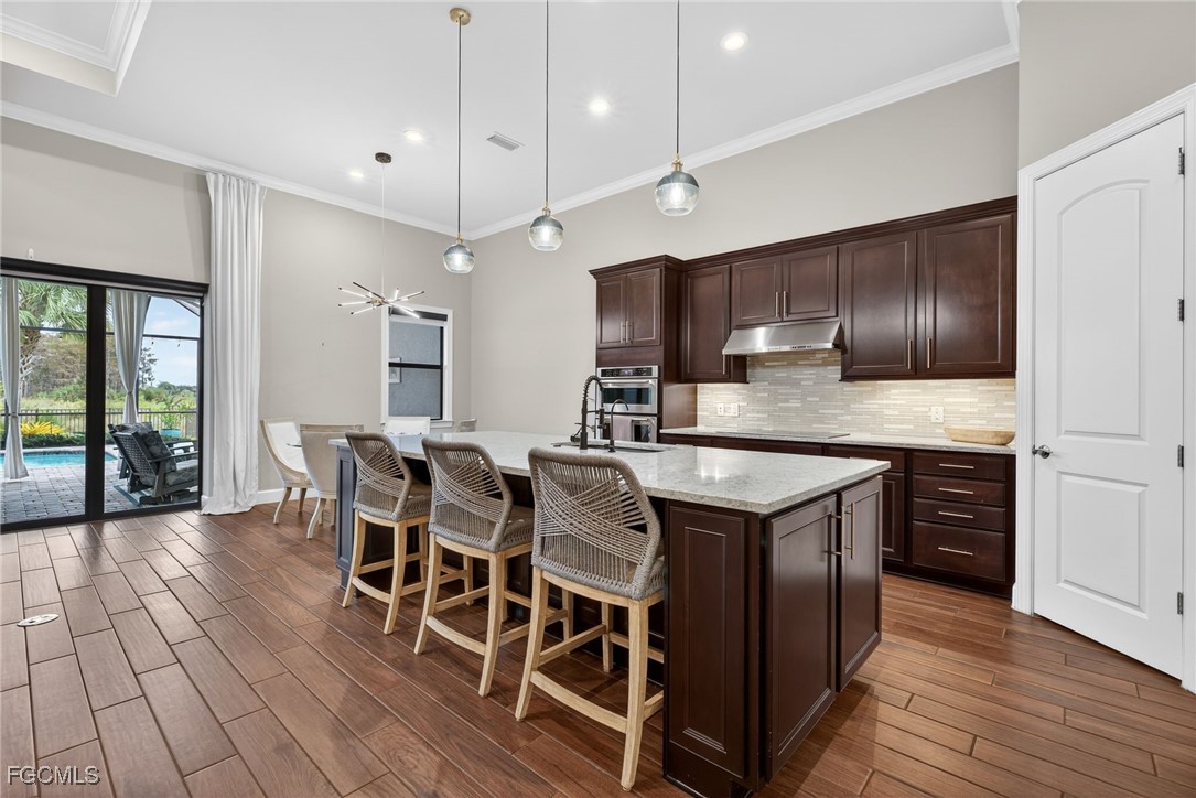 19815 Beverly Park Road Estero, FL 33928 - Photo 8 of 49 a kitchen with granite countertop stainless steel appliances a center island stools a stove a refrigerator and cabinets