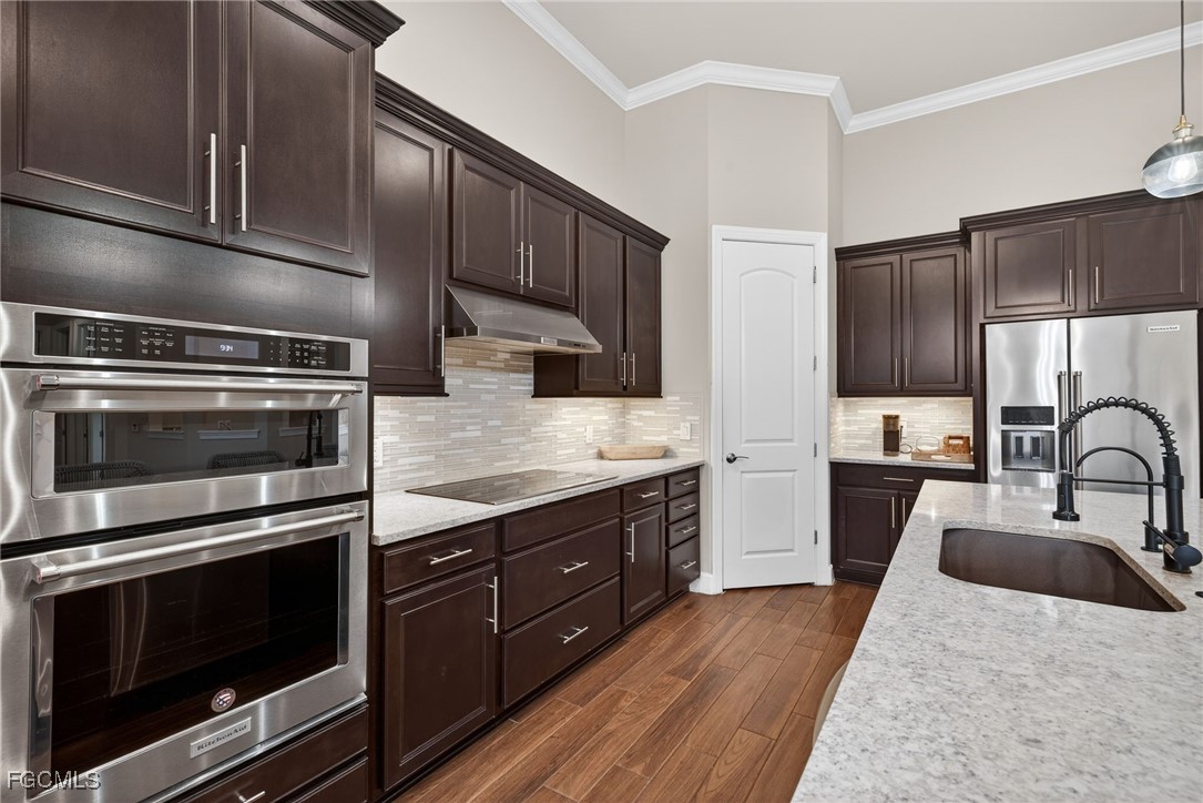 19815 Beverly Park Road Estero, FL 33928 - Photo 10 of 49 a kitchen with stainless steel appliances kitchen island granite countertop a stove a sink and a microwave