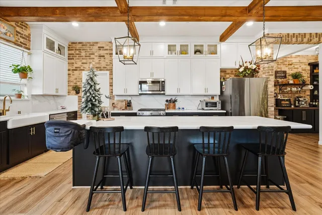 a kitchen with stainless steel appliances granite countertop a dining table chairs refrigerator and cabinets