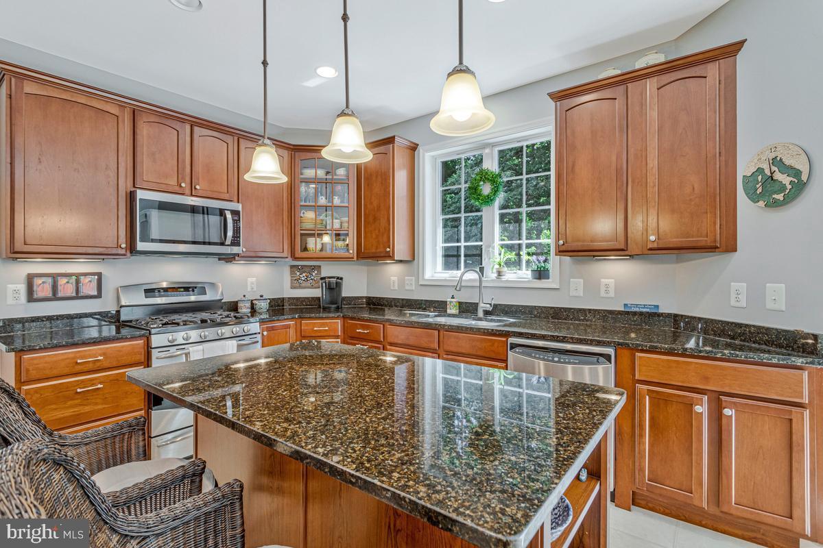 11565 Magnolia Court Issue, MD 20645 - Photo 15 of 68 a kitchen with stainless steel appliances granite countertop a stove top oven a sink dishwasher a dining table and chairs with wooden floor