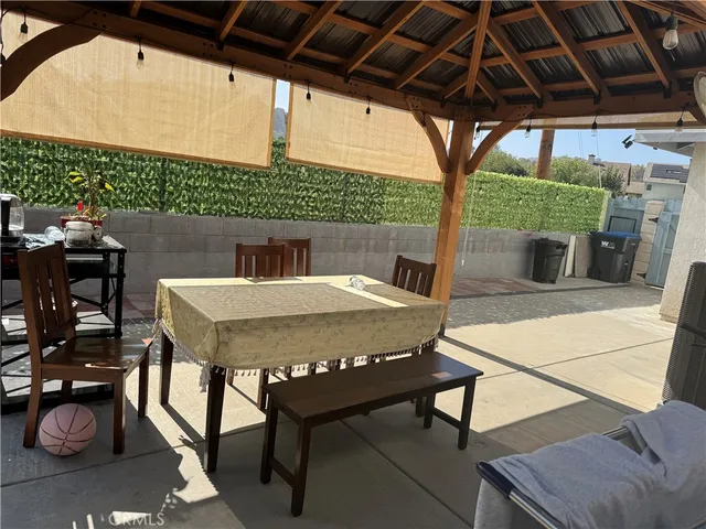 a view of a patio with table and chairs under an umbrella with a small yard