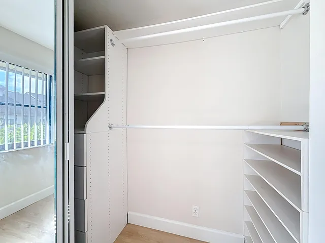 a view of an empty room with wooden floor and a ceiling fan
