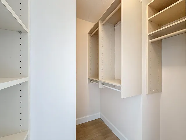 a view of an empty room with wooden floor and a ceiling fan
