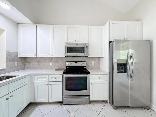 a kitchen with white cabinets and stainless steel appliances