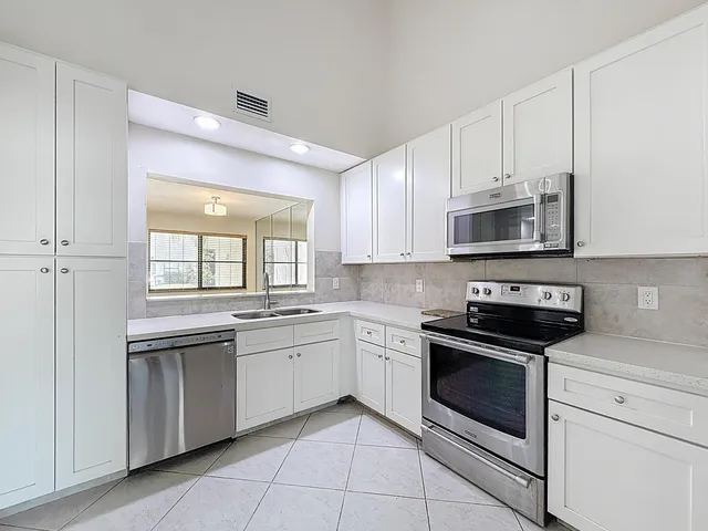 a kitchen with stainless steel appliances granite countertop white cabinets and sink