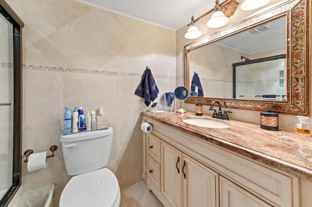a en suite bathroom with a granite countertop toilet sink and mirror