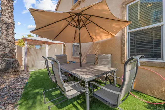 a view of a patio with a table and chairs under an umbrella