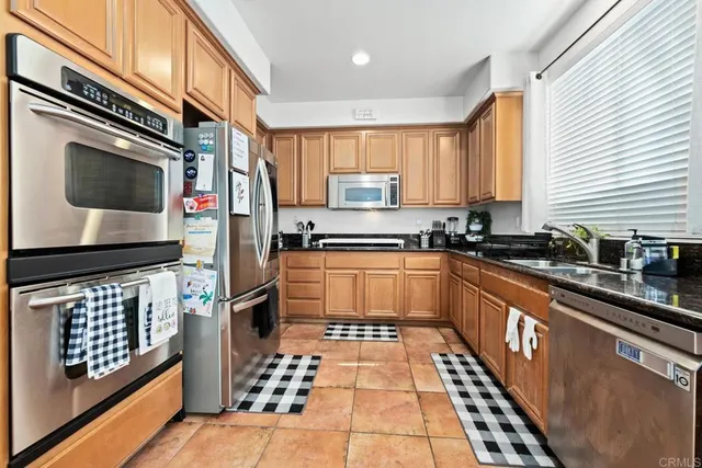 a kitchen with stainless steel appliances kitchen island granite countertop a refrigerator and a stove top oven