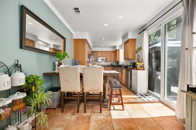 a dining room with stainless steel appliances kitchen island granite countertop a refrigerator a stove a sink with a dining table and chairs