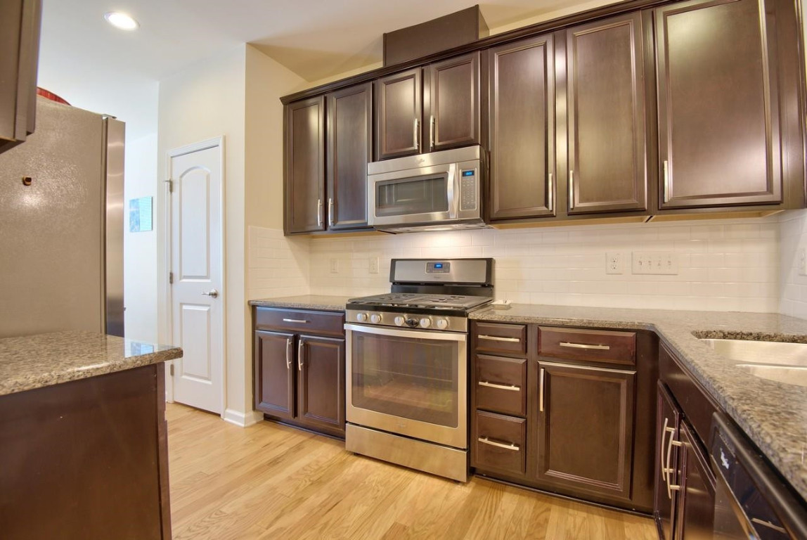 Undisclosed Address Durham, NC 27705 - Photo 7 of 25 a kitchen with stainless steel appliances granite countertop wooden cabinets and a stove top oven