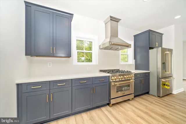 a large white kitchen with stainless steel appliances a stove and a sink
