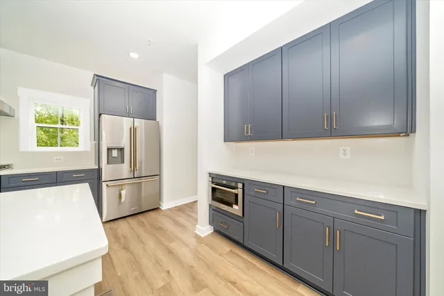 a large white kitchen with a large window and stainless steel appliances