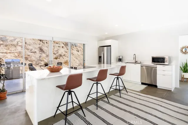 a living room with stainless steel appliances kitchen island granite countertop furniture and a rug