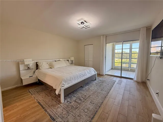 a spacious bedroom with a bed and wooden floor